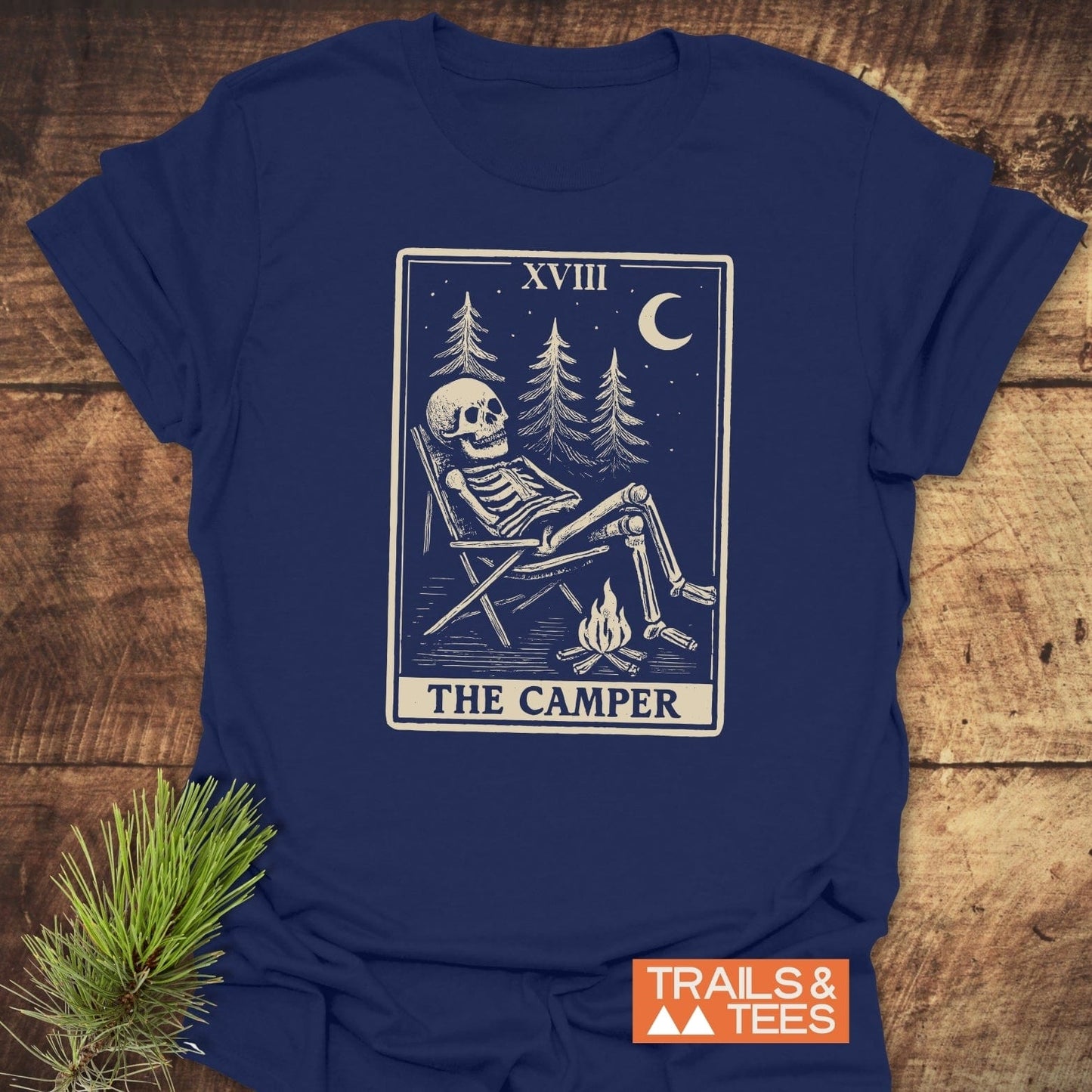 The Camper Tarot T-Shirt features a skeleton by a campfire illustration, Roman numeral XVIII, brand TRAILS & TEES, crafted for outdoor comfort and adventure.