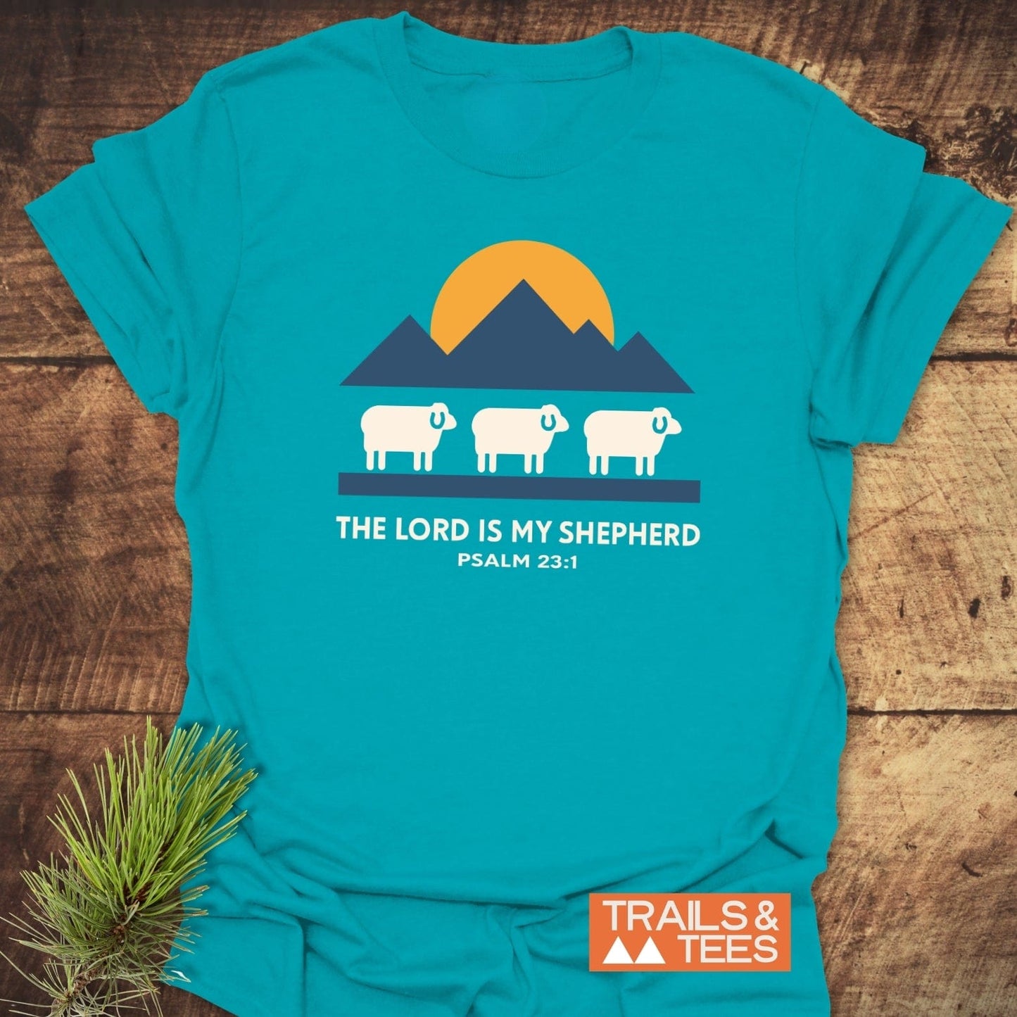 The Lord Is My Shepherd T-Shirt features a sheep graphic with mountains and sun, made from soft cotton for comfort and durability, perfect for outdoor enthusiasts.