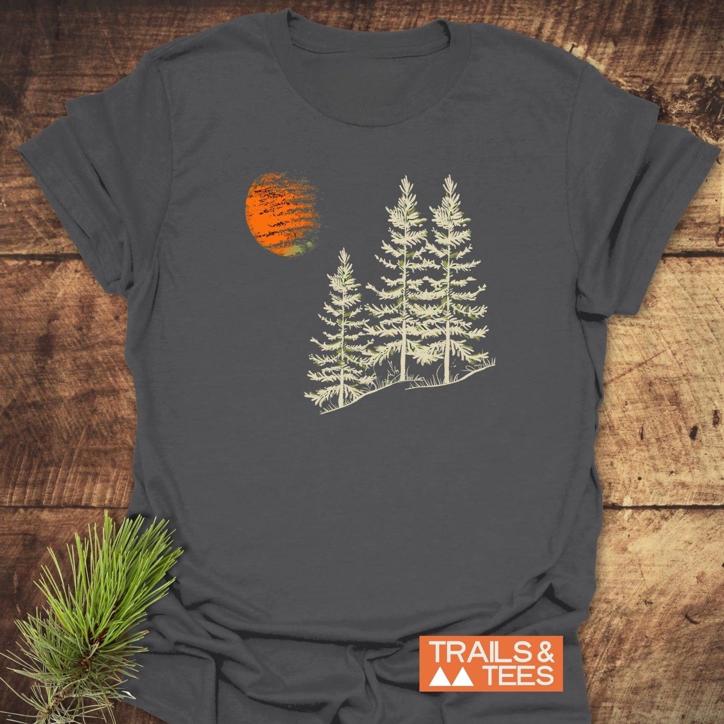 Forest And Moon T-Shirt featuring stylized pine trees and a sunset. Made from soft ring-spun cotton, ensuring comfort and durability for outdoor adventures.
