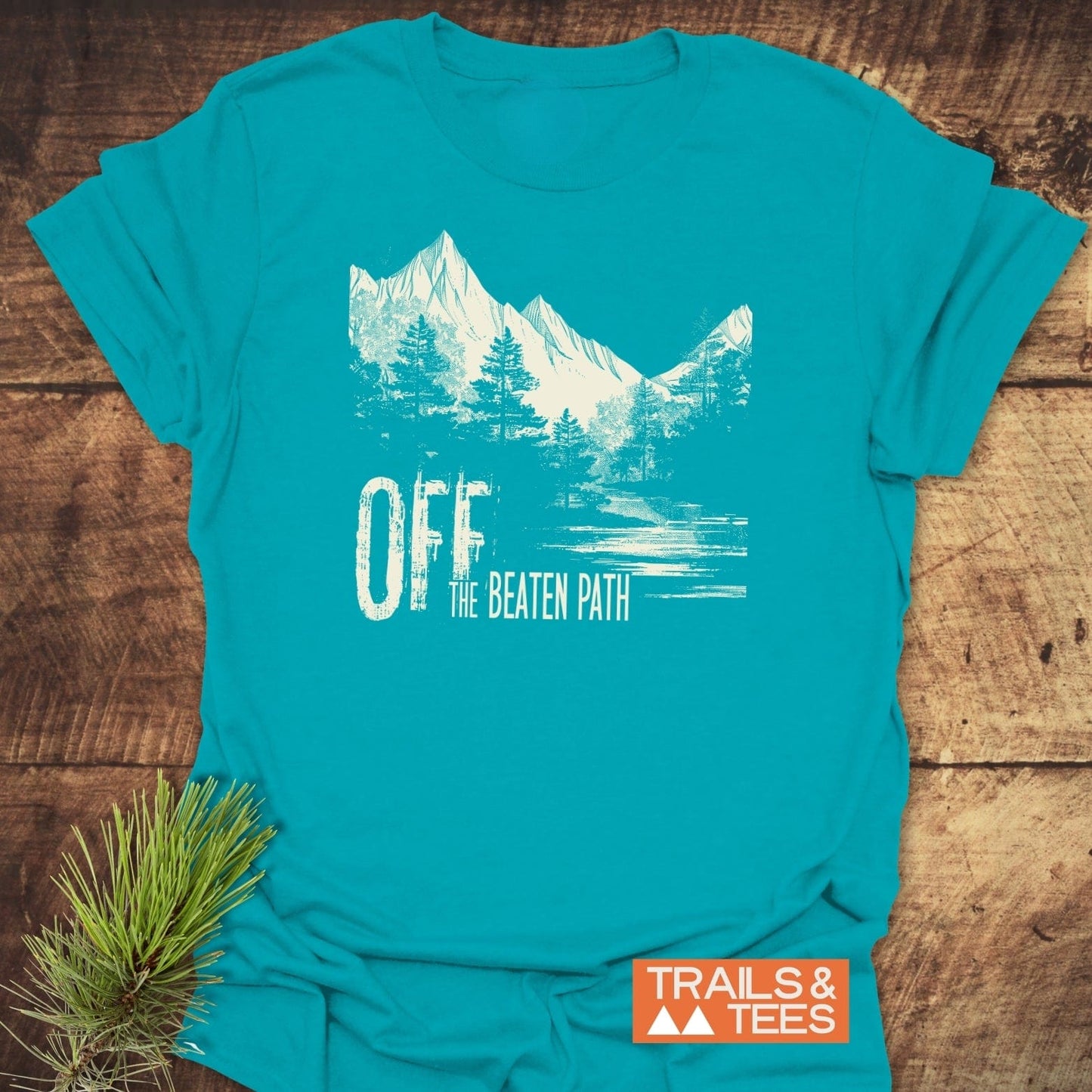 Off The Beaten Path T-Shirt featuring a mountain and pine tree design, highlighting its soft, durable cotton for outdoor enthusiasts.