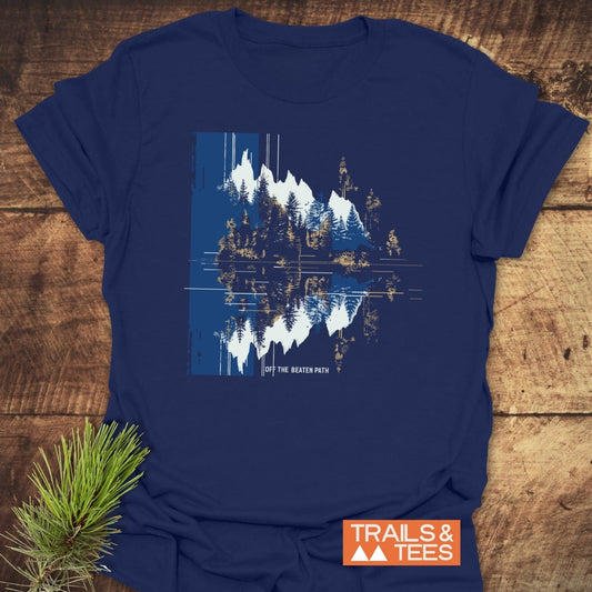 Minimalist Mountain Reflection T-Shirt featuring snow-capped mountains and trees with a glitch effect, slogan “Off the Beaten Path,” on soft, durable cotton.