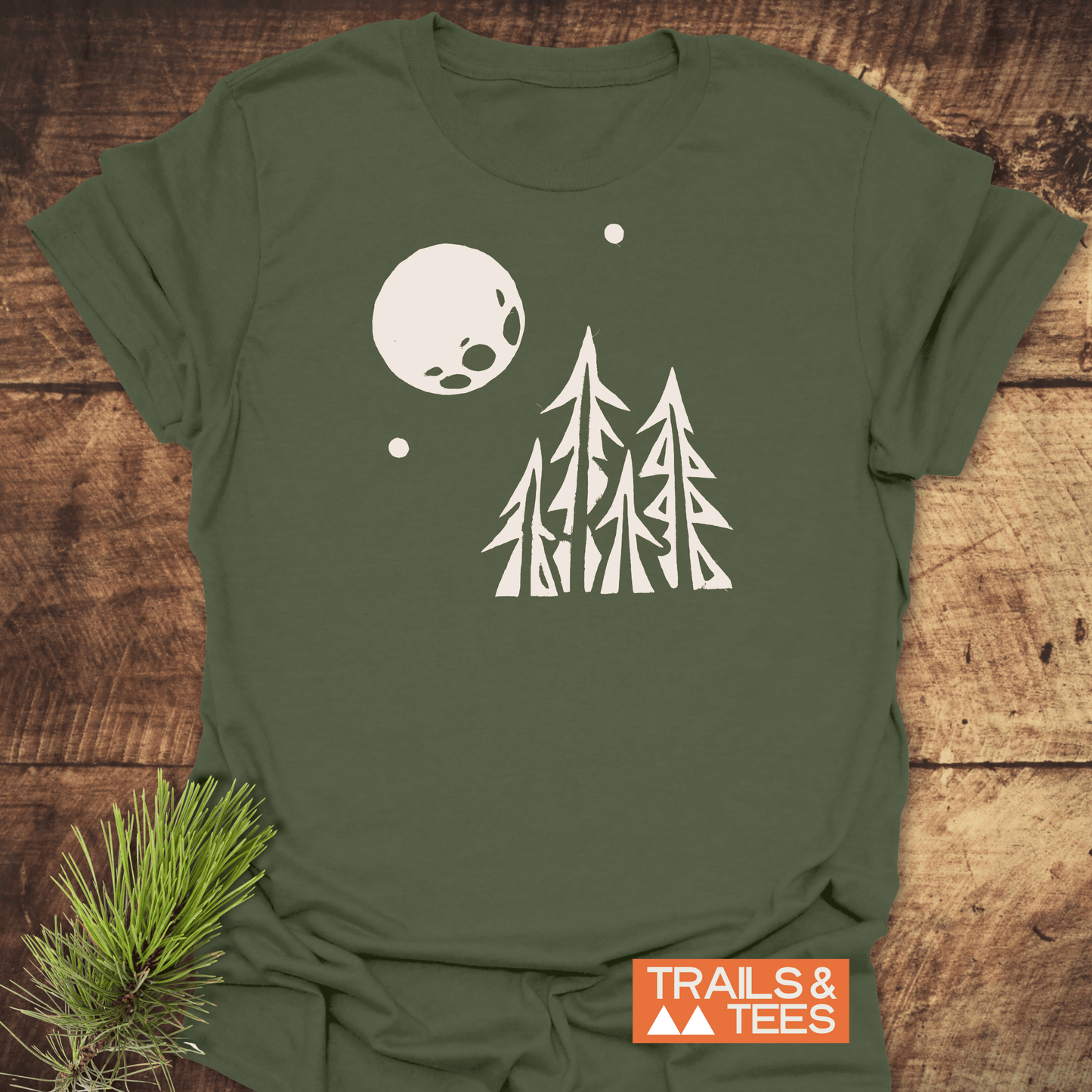 Pine Trees and Full Moon T-Shirt featuring a minimalist forest scene. Crafted from soft ring-spun cotton, ideal for outdoor enthusiasts. Branded “TRAILS & TEES.”