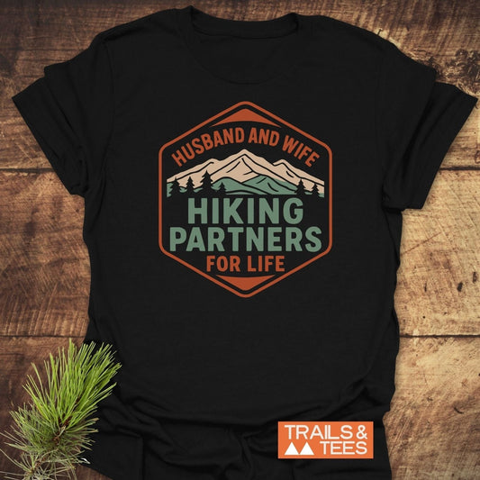 Hiking Partners For Life T-Shirt featuring a mountain and pine tree graphic, crafted from soft ring-spun cotton, displayed flat with pine sprig, brand logo visible.