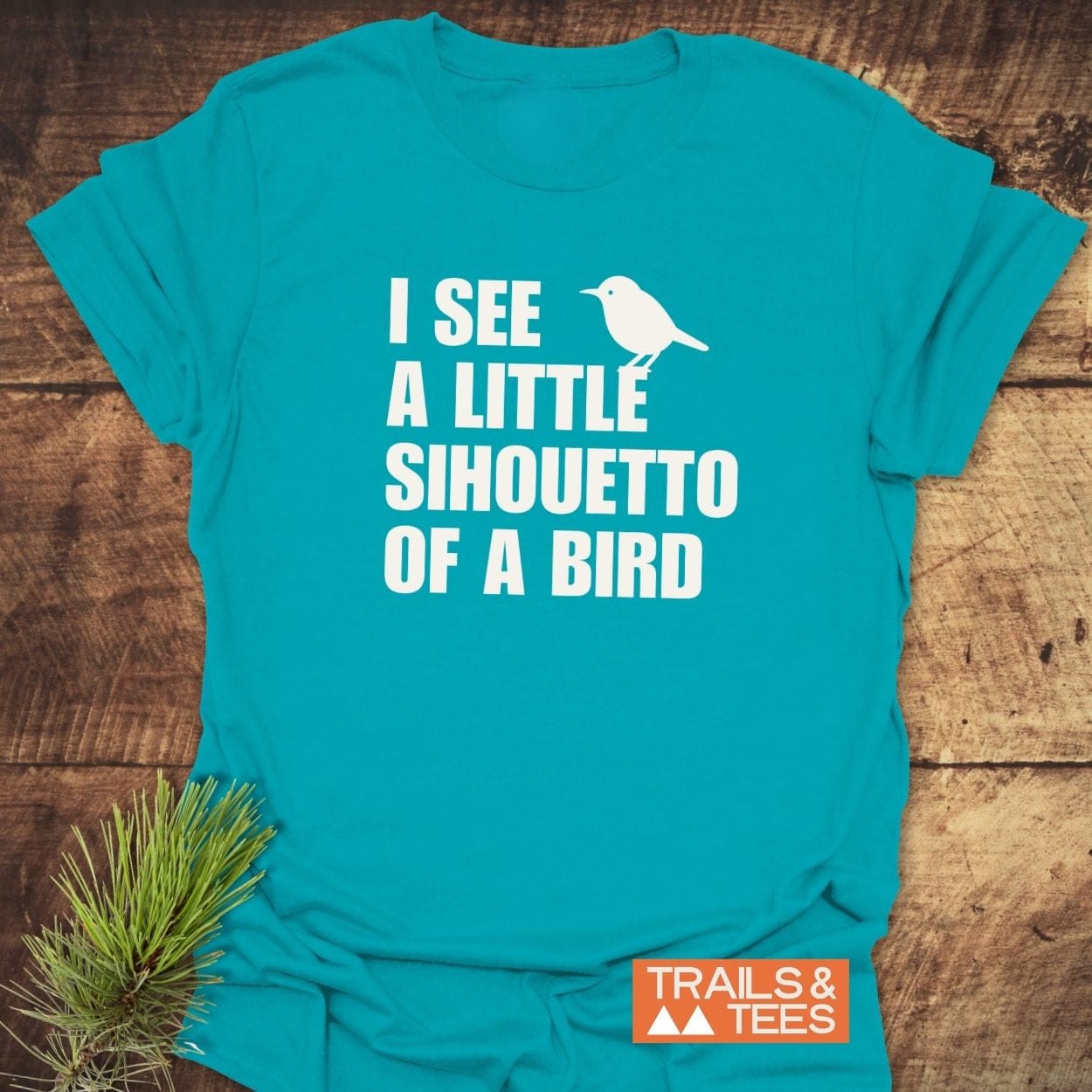 Silhouetto Of A Bird Funny T-Shirt displayed, featuring a bird graphic and phrase. Made from soft cotton, durable print, brand logo “TRAILS & TEES” visible.