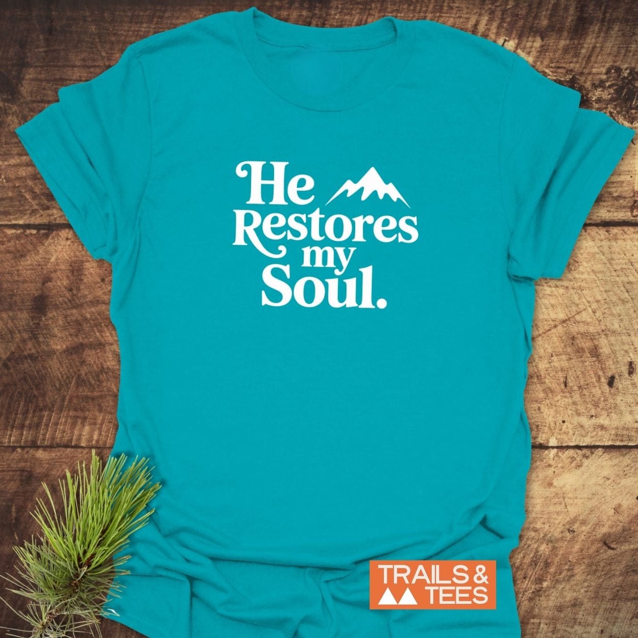 He Restores My Soul T-Shirt with mountain silhouette, crafted from soft ring-spun cotton, featuring durable, crack-resistant print, and TRAILS & TEES logo.
