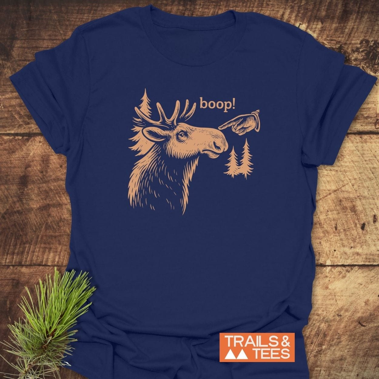 BOOP Moose Funny T-Shirt: Navy-blue tee with moose and trees design, boop! text, and TRAILS & TEES. logo, highlighting comfort and durability for outdoor enthusiasts.