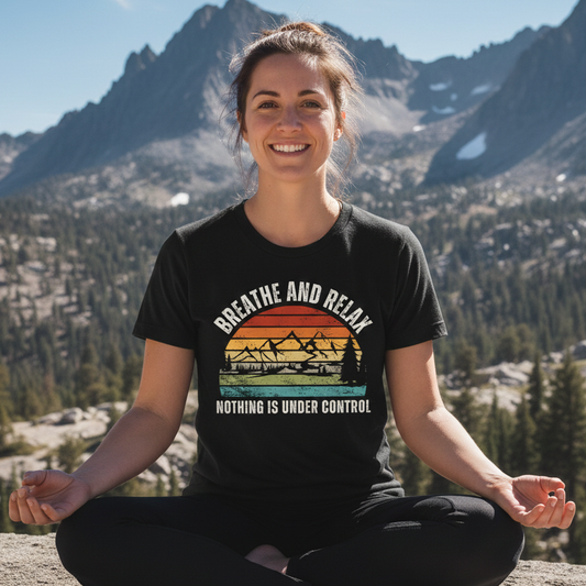 Young woman outdoors in meditation, wearing the Breathe And Relax Funny T-Shirt with sunset-mountains graphic, conveying a relaxed vibe amidst mountainous scenery, embodying adventure and comfort.