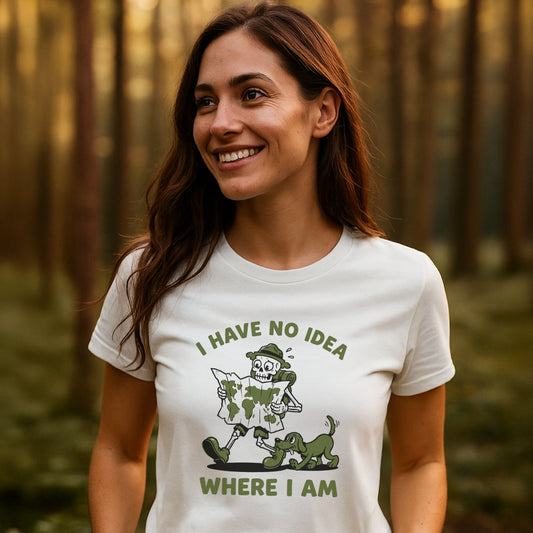 Woman in a forest wearing the Lost Skeleton Hiker T-Shirt featuring a cartoon skeleton hiker with a dog, and the text I HAVE NO IDEA WHERE I AM. Crafted for outdoor adventures.