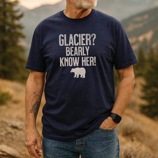 Adult man outdoors wearing the Glacier National Park Funny T-Shirt with distressed white text and bear silhouette, showcasing its soft cotton fabric and taped shoulder design for comfort and durability.