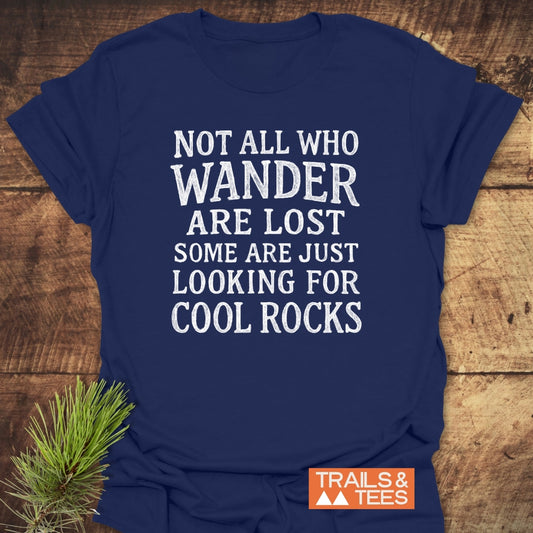 Not All... Rustic Chalkboard T-Shirt featuring a distressed white slogan on navy-blue fabric, laid flat on wood. Includes an orange “TRAILS & TEES.” logo, emphasizing durable, adventure-ready wear.