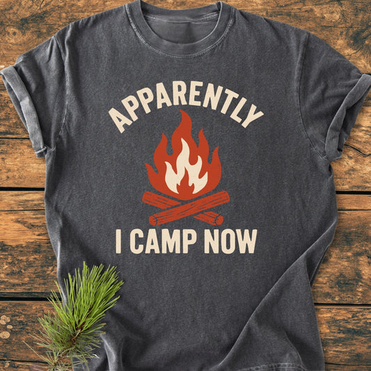 Apparently Camping - Vintage Wash Tee featuring a stylized camping fire and slogan laid flat on wood. Made from 100% ring-spun cotton, it offers durability and comfort with a relaxed fit.