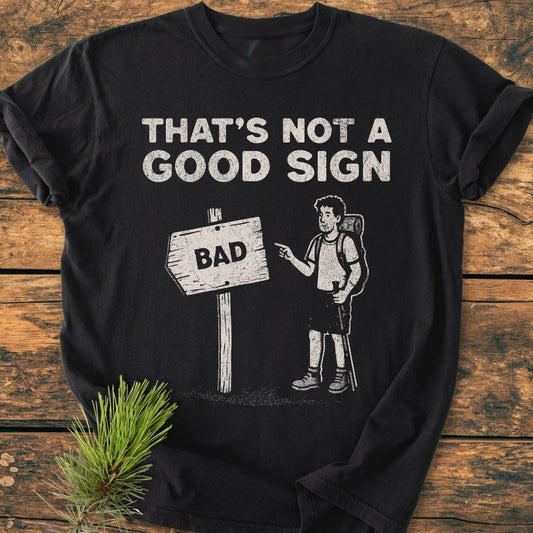 Bad Sign - Vintage Wash Tee: Black T-shirt with white graphic and text THAT’S NOT A GOOD SIGN featuring a cartoon hiker pointing at a directional sign reading BAD, highlighting a visual pun.
