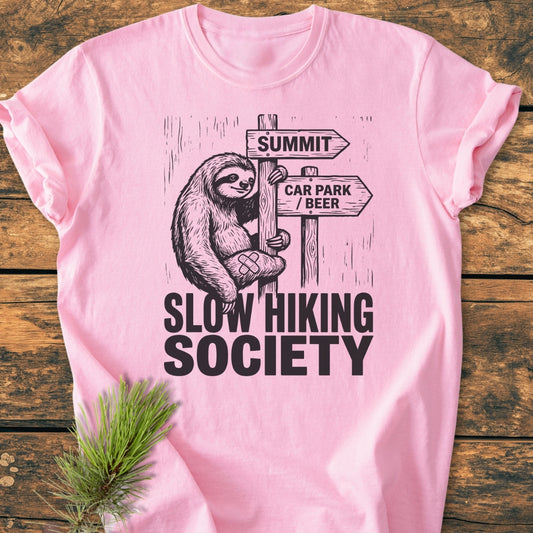The Slow Hiking Society - Vintage Wash Tee features a cartoon sloth on a signpost with arrows labeled SUMMIT and CAR PARK / BEER, emphasizing a relaxed, adventurous spirit.