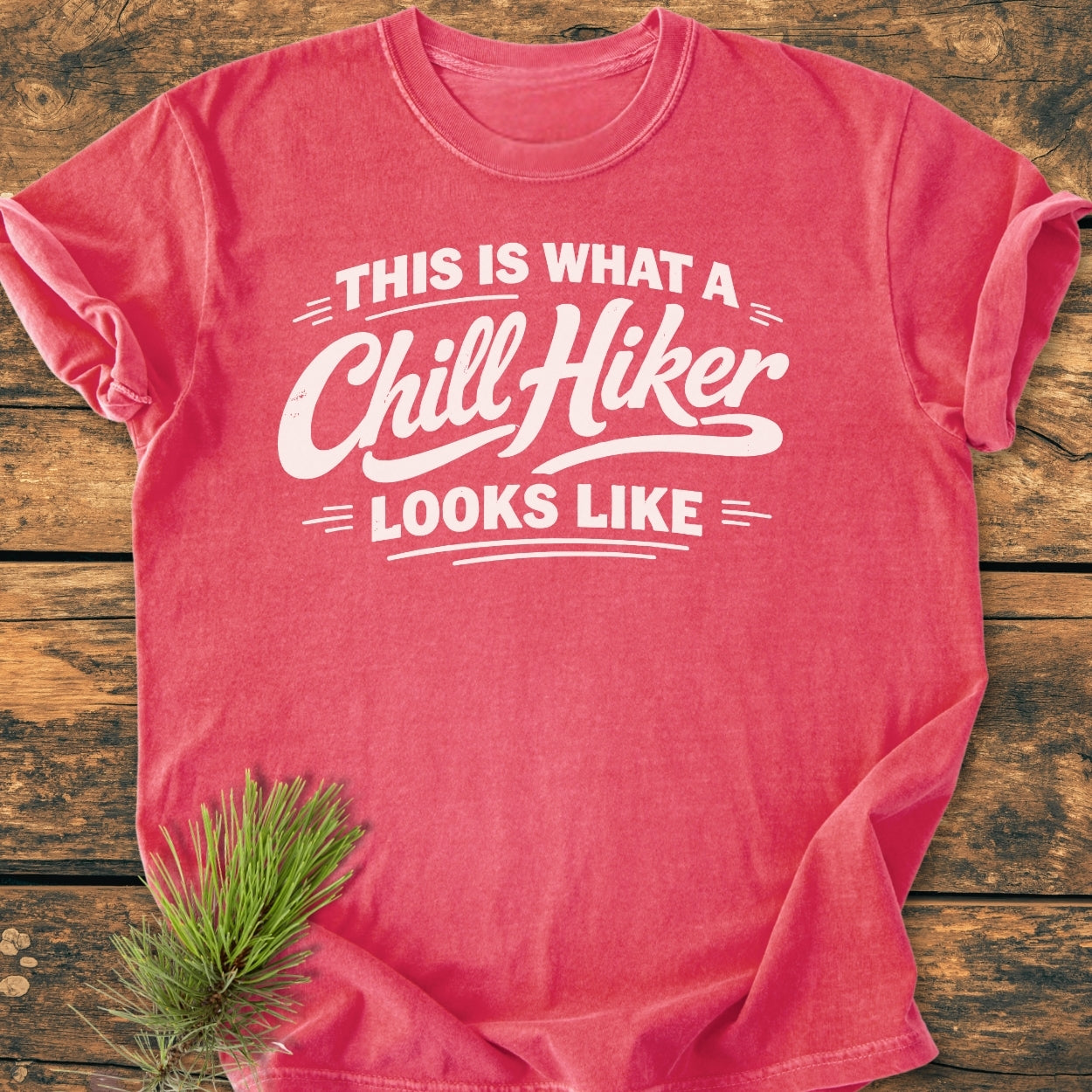 Chill Hiker - Vintage Wash Tee, featuring bold white lettering on a red-coral crew-neck, laid flat with a pine branch accent, showcasing a relaxed fit and durable, soft-washed cotton fabric.