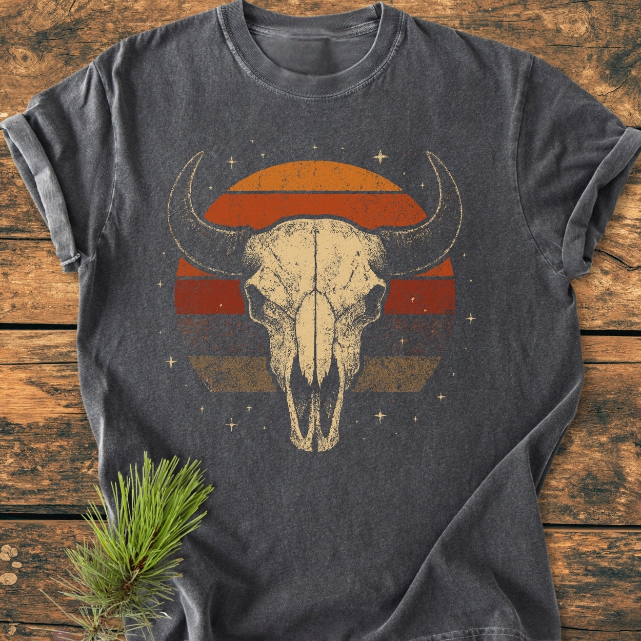 Retro Buffalo Skull - Vintage Wash Tee featuring a distressed bison skull and sunset graphic, laid flat on wood. Made from soft, garment-dyed cotton with a relaxed fit.