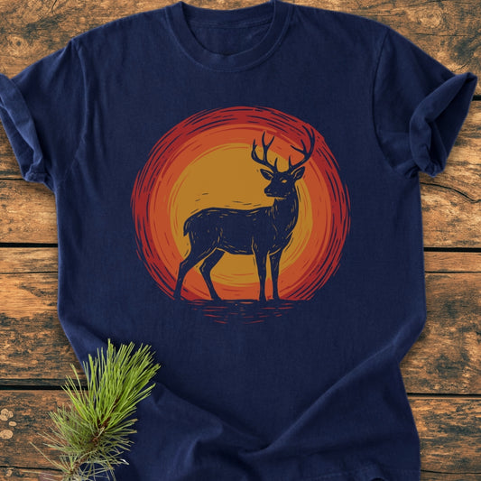 Trail Guardian - Vintage Wash Tee featuring a stag silhouette against a sunset motif, laid on a wooden surface with pine sprig; showcases relaxed fit and durable, soft-washed cotton fabric.