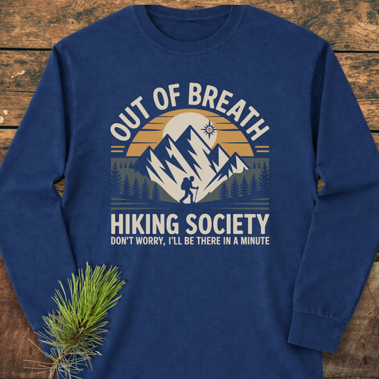 Out Of Breath Hiking Society Long-Sleeve Tee featuring a camping-themed graphic with mountains, sun, trees, and a lone hiker. Made of 100% ring-spun cotton for comfort and style.