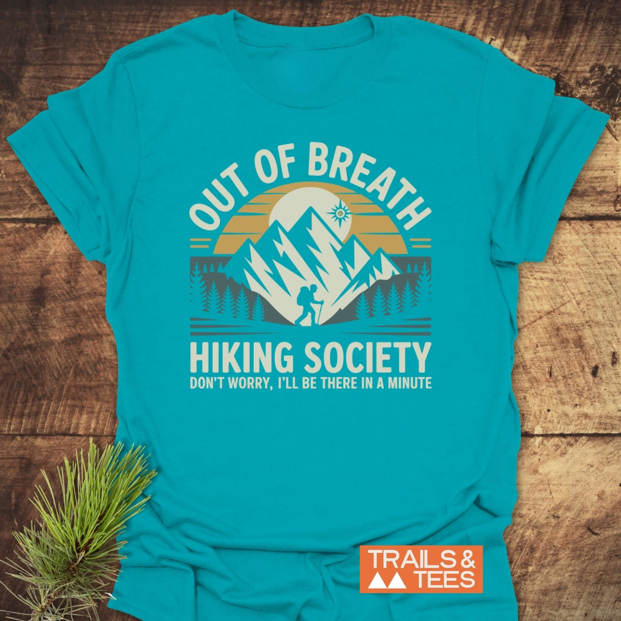 Out Of Breath Hiking Society T-Shirt featuring a mountain scene with a hiker and pine trees, complemented by playful text about hiking delays. Designed for comfort and durability, perfect for outdoor enthusiasts.