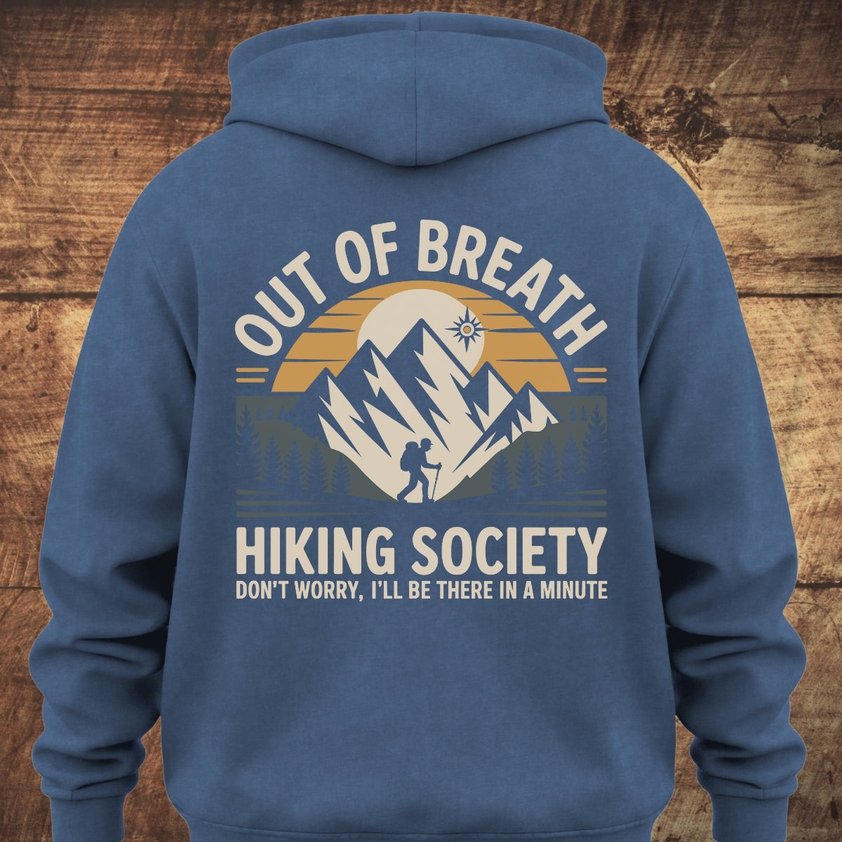 Out Of Breath Hiking Society BACKPRINT hoodie featuring a stylized mountain, sun, and hiker graphic. Text reads: OUT OF BREATH, HIKING SOCIETY, and DON’T WORRY, I’LL BE THERE IN A MINUTE.
