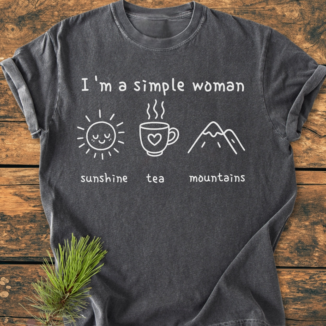 I'm A Simple Woman. Sunshine, Tea, Mountains - Vintage Wash Tee displayed flat with sunshine, tea, and mountains icons on charcoal-gray fabric, showcasing its relaxed fit and durable stitching.