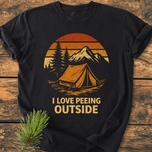 I LOVE Peeing Outside - Vintage Wash Tee features a retro camping scene with pine trees, tent, and mountains on a black T-shirt, offering a relaxed fit with durable, soft-washed cotton.