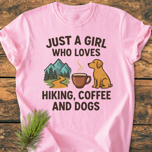Just A Girl... Hiking Coffee Dogs - Vintage Wash Tee featuring bold text and icons of a mountain, coffee mug, and dog on a pink Comfort Colors garment-dyed, relaxed fit T-shirt.