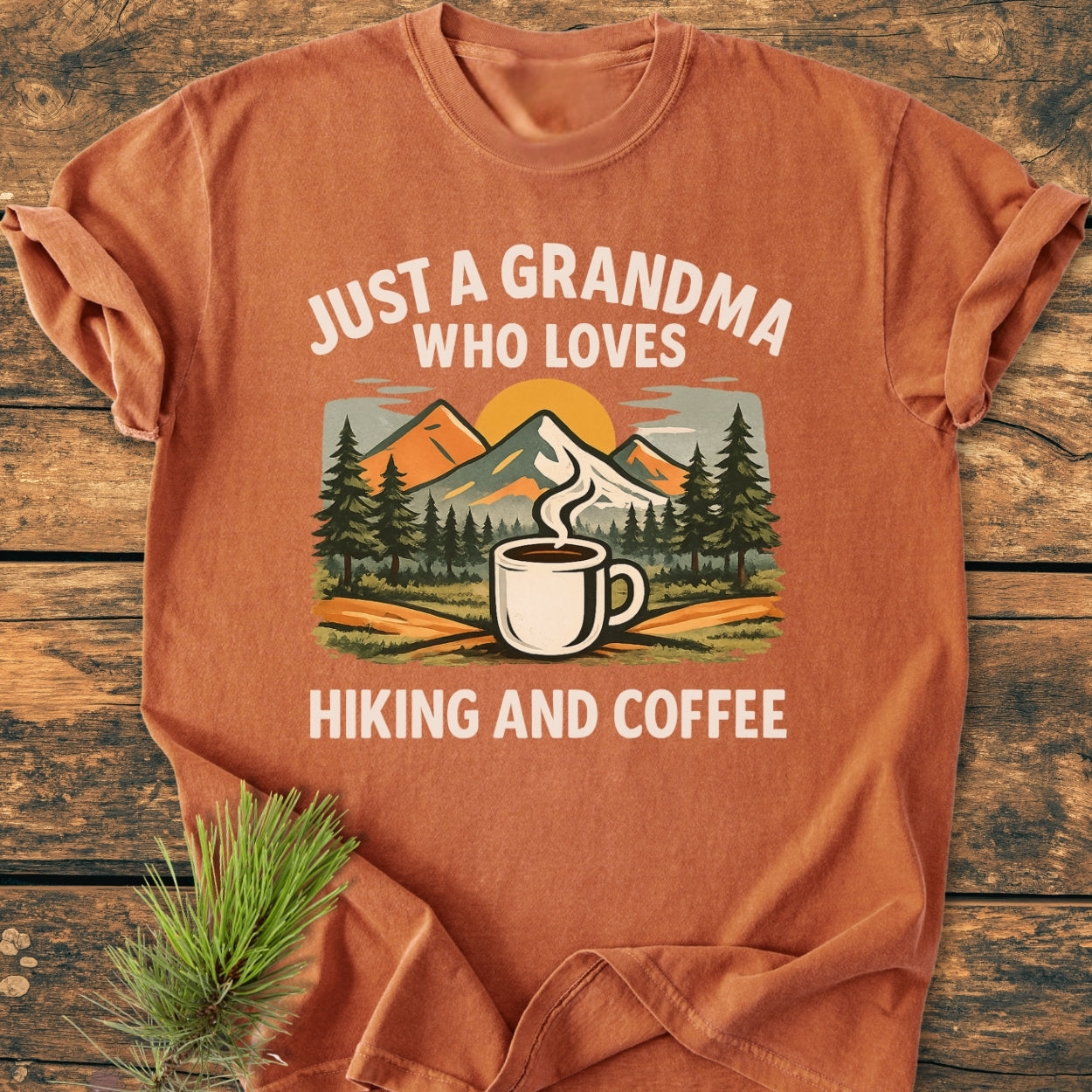 Grandma Loves Hiking And Coffee - Vintage Wash Tee features a mountain-forest scene and coffee mug print on an orange-rust shirt, emphasizing comfort with soft-washed, durable ring-spun cotton.