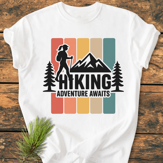 Hiking Girl - Vintage Wash Tee featuring a retro graphic of a hiker, pine trees, and mountains, laid on wood. Made from soft, durable 100% ring-spun cotton, perfect for daily wear.