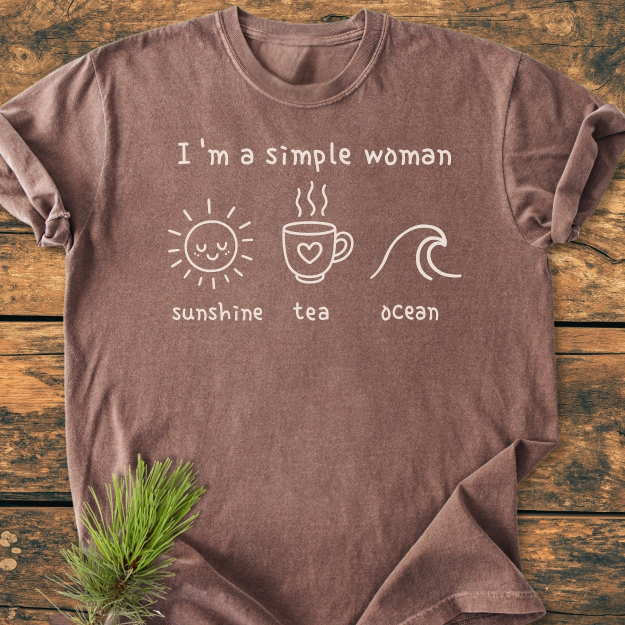 I'm A Simple Woman - Sunshine Tea Ocean - Vintage Wash Tee with graphic of sun, mug, and wave on front, laid on wooden surface, featuring soft, garment-dyed fabric and relaxed fit.