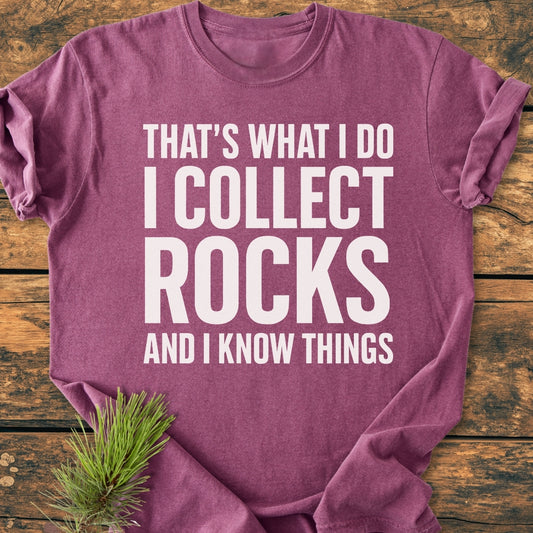 I Collect Rocks - Vintage Wash Tee featuring a slogan in white letters. Laid on wooden planks, pine needles accent the scene, showcasing the tee's relaxed fit and robust double-needle stitching.