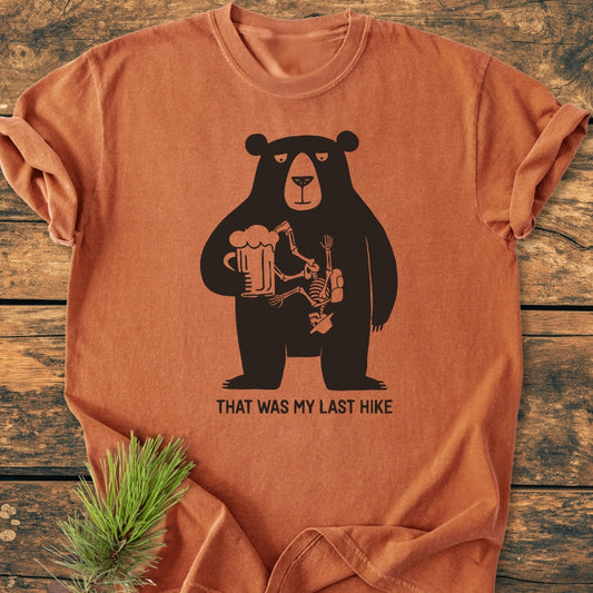 That Was My Last Hike - Vintage Wash Tee: Rust-orange T-shirt featuring a black bear with a beer mug and hiker bones design, captioned humorously. Cozy, relaxed fit, durable, made from 100% ring-spun cotton.