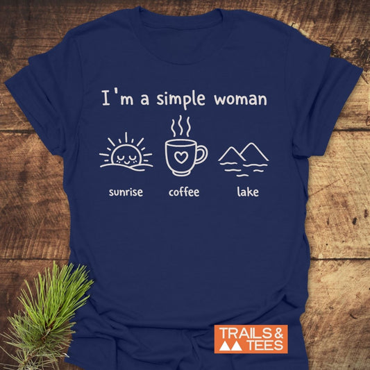 I'm A Simple Woman - Sunrise Coffee Lake T-Shirt features a navy-blue shirt with icons: sunrise, coffee, lake. TRAILS & TEES brand tag visible, embodying outdoor adventure spirit and comfort.