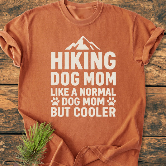 Hiking Dog Mom - Vintage Wash Tee on wood, featuring white mountain silhouette and paw prints. Soft, rust-orange fabric, relaxed fit, durable stitching, perfect for daily wear.