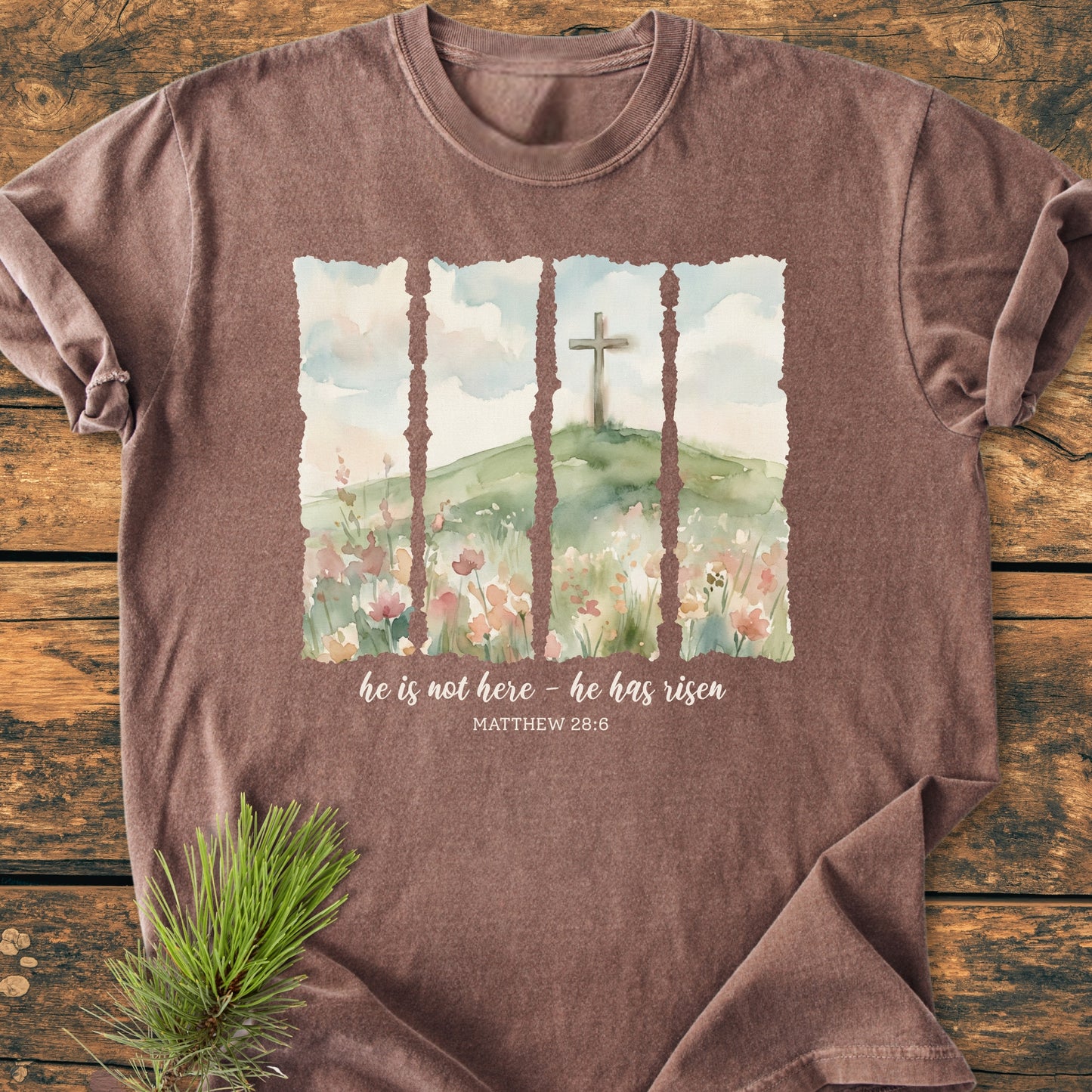 He Is Not Here. He Has Risen - Vintage Heavyweight Tee features a watercolor scene with wildflowers, a grassy hill, and a wooden cross, accompanied by Matthew 28:6 inscription on soft, durable cotton.