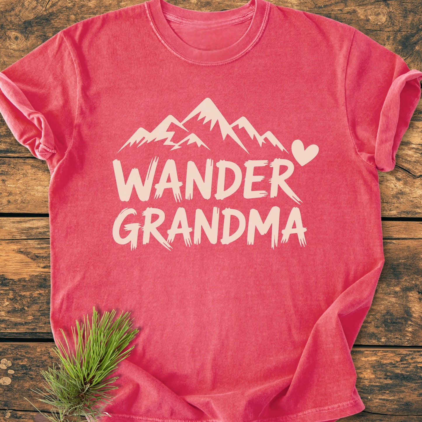 Wander Grandma - Vintage Heavyweight Tee features a mountain design with a heart on a rustic wooden backdrop. This relaxed fit, garment-dyed cotton tee ensures comfort and durability with its soft-washed texture.