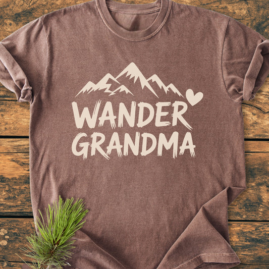 Heather-brown Wander Grandma - Vintage Heavyweight Tee with cream mountain graphic and heart, laid flat on wood. Features soft, durable, 100% ring-spun cotton. Includes pine sprig accent.