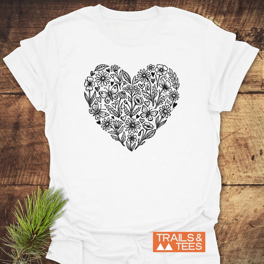 Wildflower Heart Butterfly Soul Softstyle T-Shirt, featuring a black line art heart of wildflowers and butterflies, set against a rustic backdrop. Includes TRAILS & TEES logo in the corner.