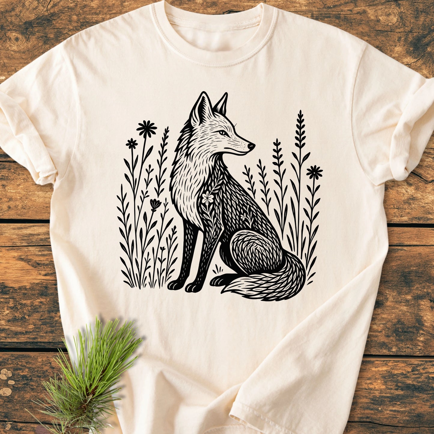 Cream-colored 225 Wildflower Fox DARK T-shirt with a black fox graphic among wildflowers, laid flat on wood, highlighting its soft, durable fabric and relaxed fit for everyday comfort.