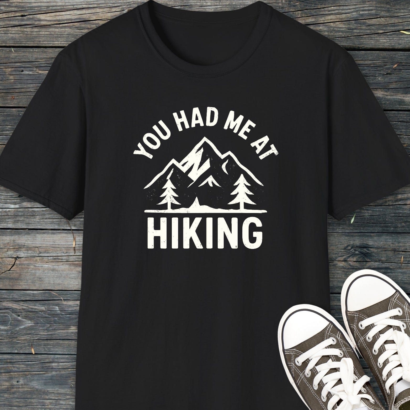 You Had Me At Hiking T-Shirt with mountain graphic, paired with canvas sneakers on wooden surface, highlighting comfort and adventure-ready design.