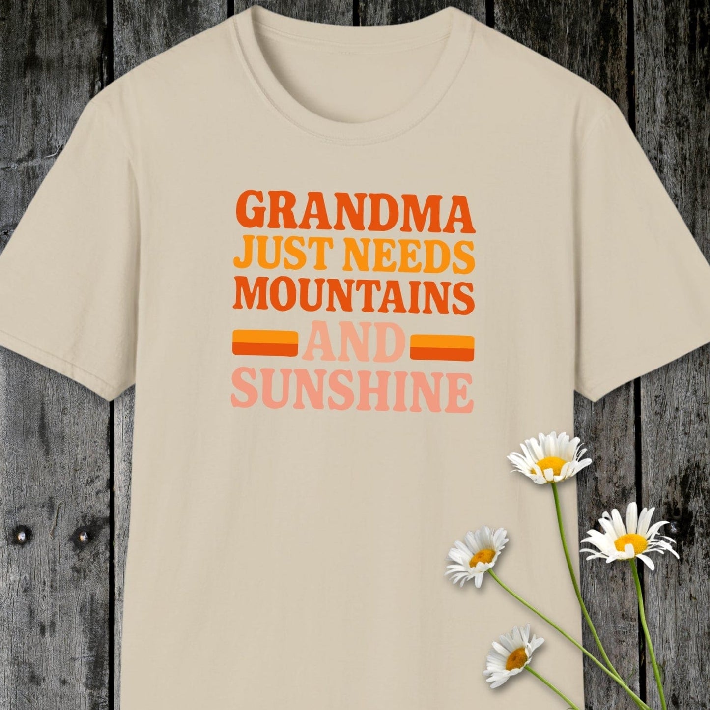 Retro 80s Grandma Mountains T-Shirt on rustic wood, featuring a colorful slogan. Soft, ring-spun cotton, ideal for outdoor adventures and everyday comfort.