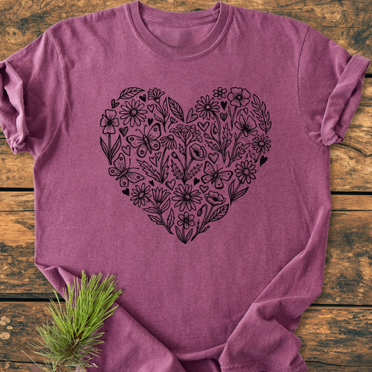 Wildflower Heart Butterfly Soul - Vintage Heavyweight Tee features a black line-art heart with flowers, leaves, and butterflies on a soft, heathered-raspberry T-shirt, laid on a rustic wooden surface.