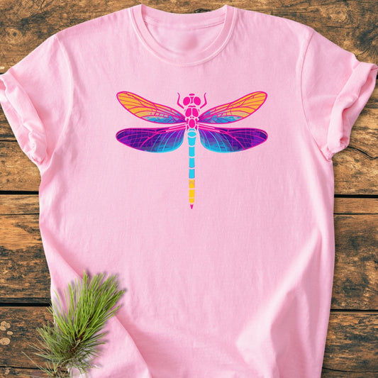 Psychedelic Dragonfly - Vintage Wash Tee features a vibrant dragonfly graphic on a pastel-pink backdrop, accentuated by a pine sprig, showcasing its relaxed fit and durable craftsmanship on a wooden surface.