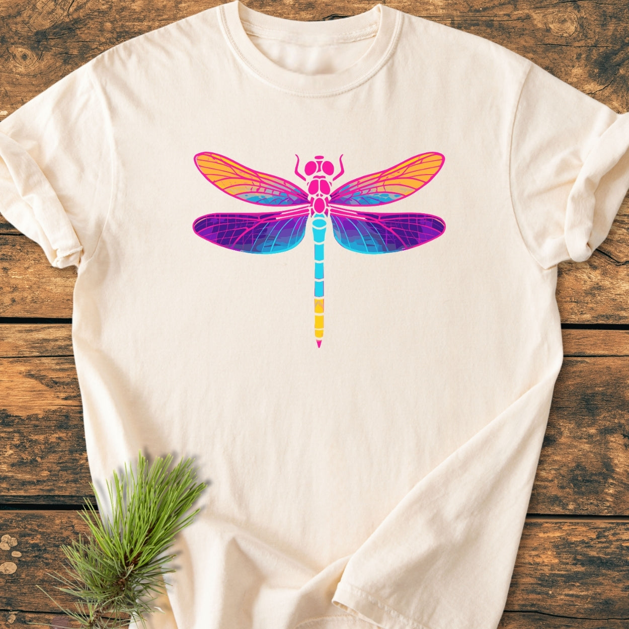 Psychedelic Dragonfly - Vintage Wash Tee features a vibrant dragonfly graphic on an off-white cotton T-shirt, laid on rustic wood, highlighting its soft, relaxed fit and durable construction.