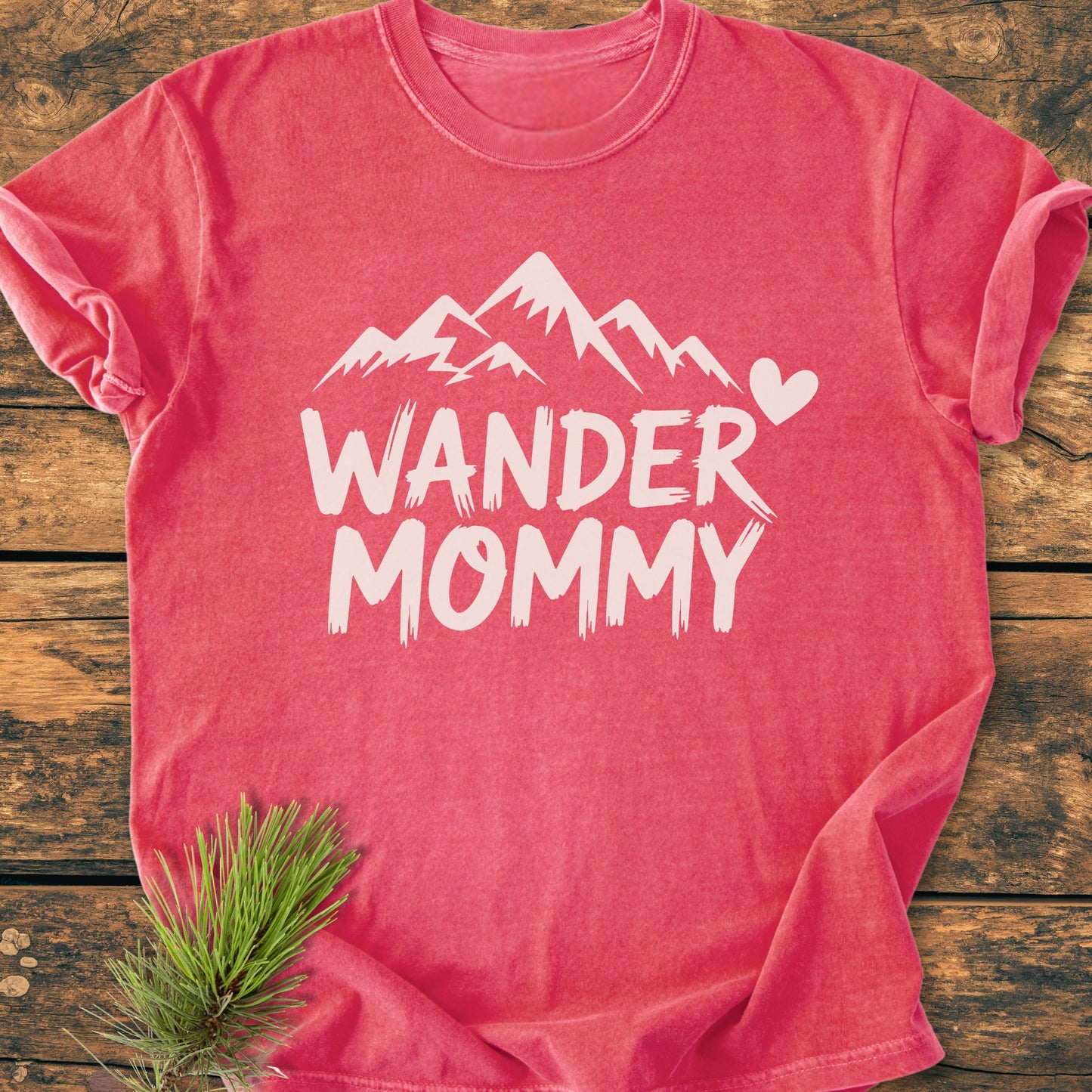 Wander Mommy - Vintage Heavyweight Tee in heather-red featuring a white mountain and heart graphic, laid flat on wood. Made of soft-washed, 100% ring-spun cotton, offering a relaxed fit.