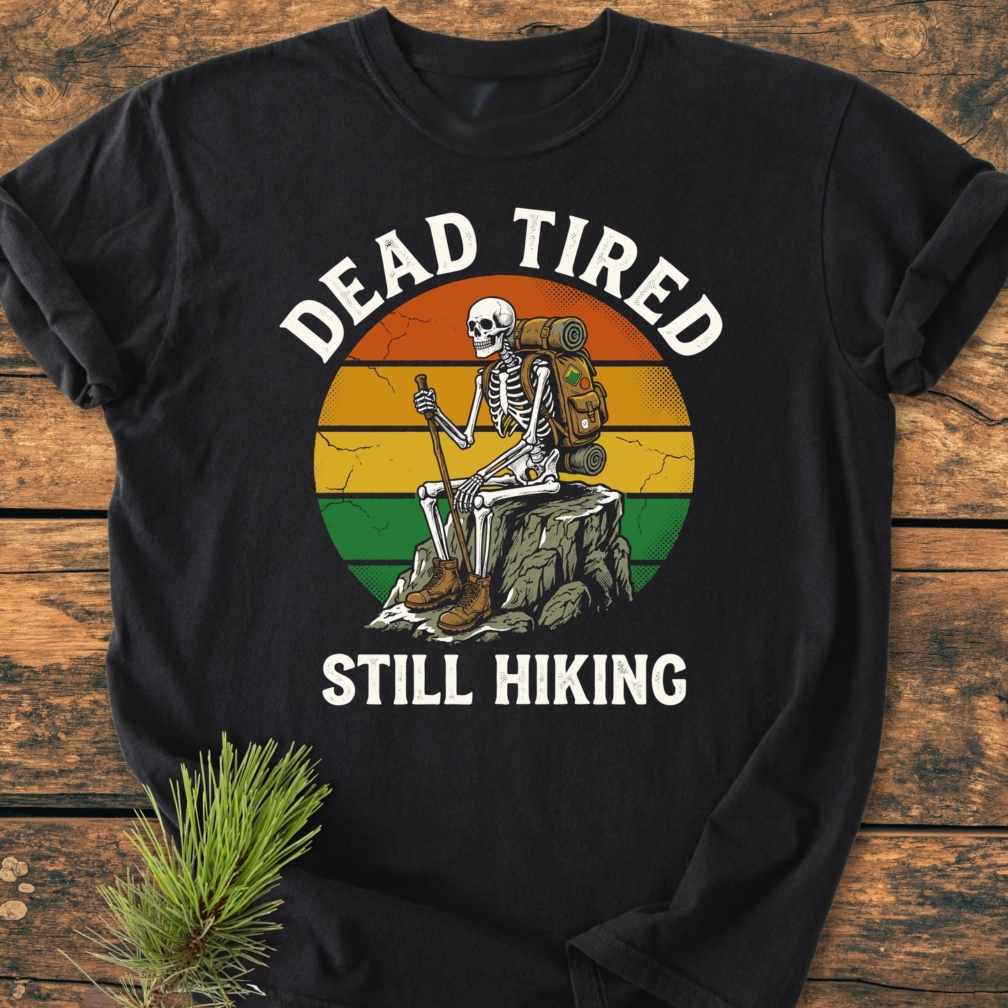 Dead Tired - Vintage Wash Tee: Black long-sleeve shirt featuring a retro-style circle with a cartoon skeleton hiking, surrounded by DEAD TIRED and STILL HIKING text, styled with a pine branch.