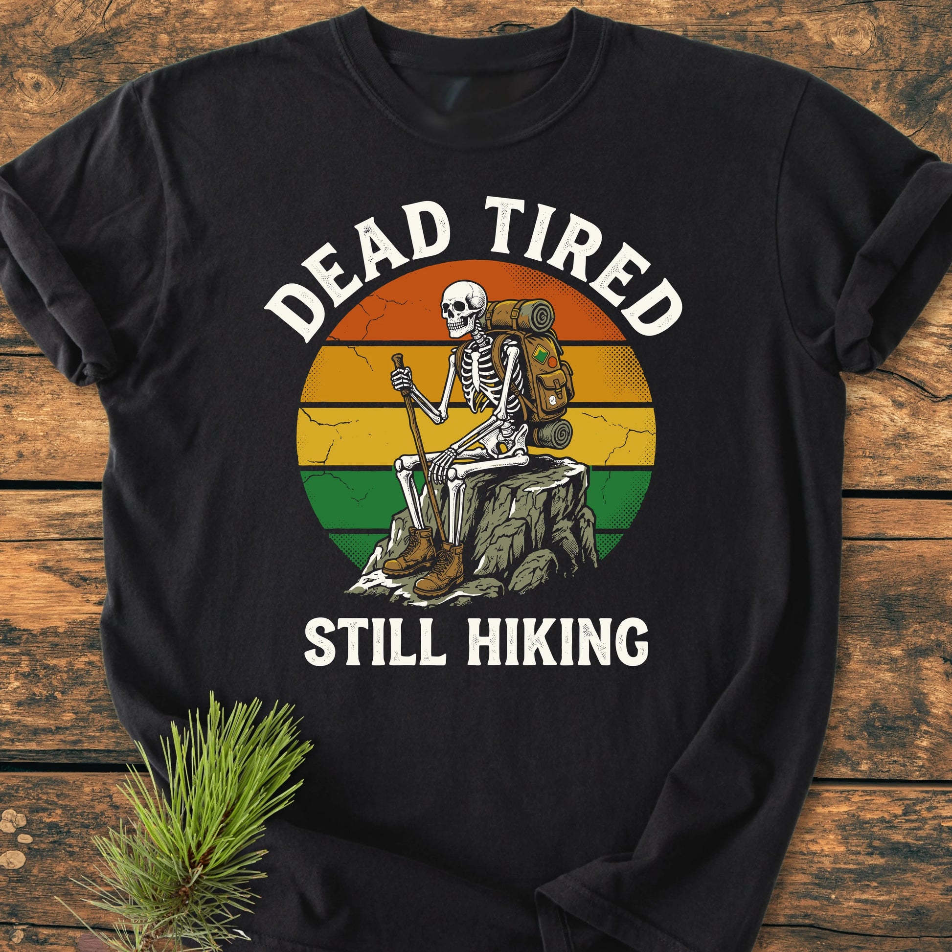 Dead Tired - Vintage Wash Tee: Black long-sleeve shirt featuring a retro-style circle with a cartoon skeleton hiking, surrounded by DEAD TIRED and STILL HIKING text, styled with a pine branch.