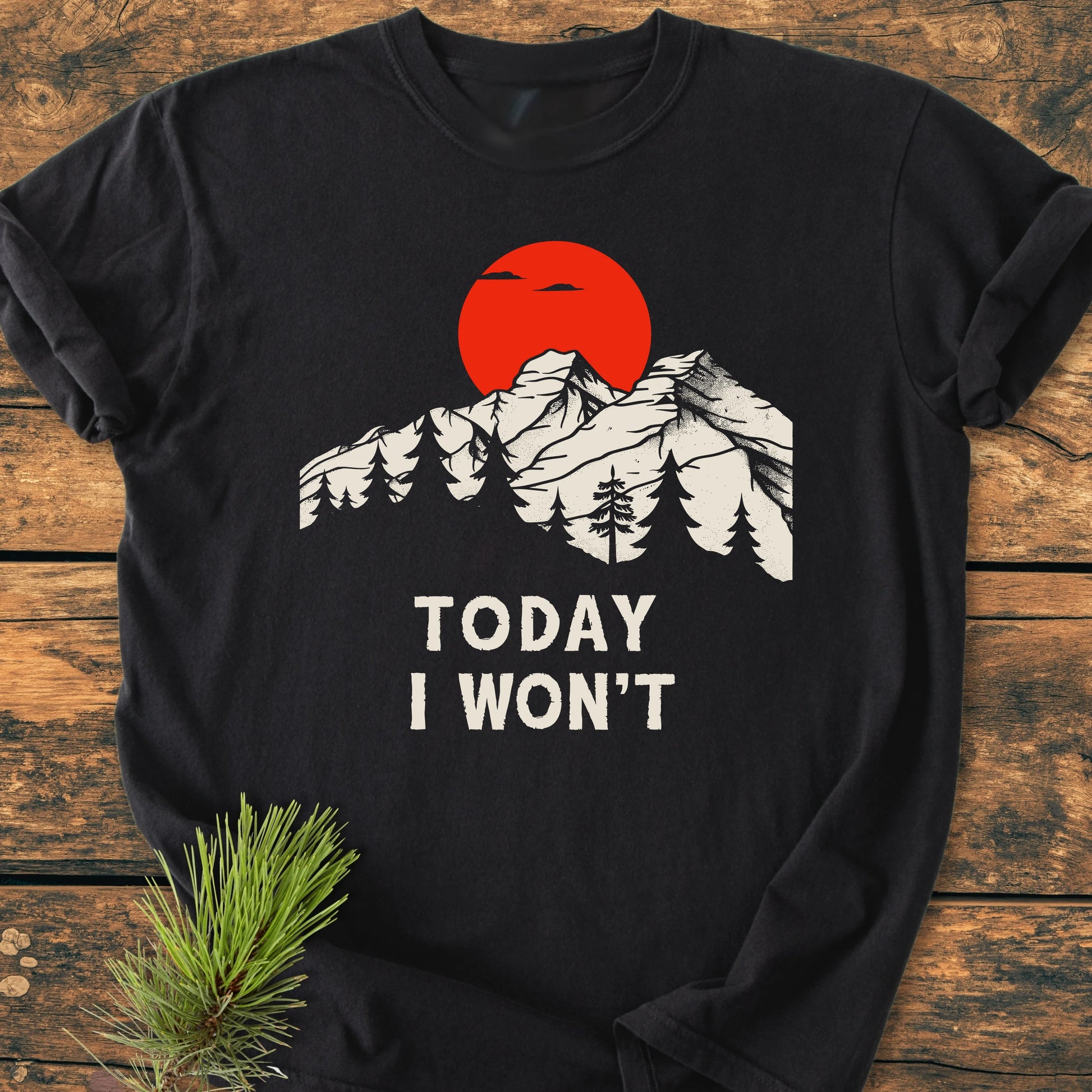 Black long-sleeve tee 1423 Today I Won't with snow-capped mountains, pine trees, and red sun graphic, laid on wooden surface, embodying a vintage, lived-in look for everyday adventures.