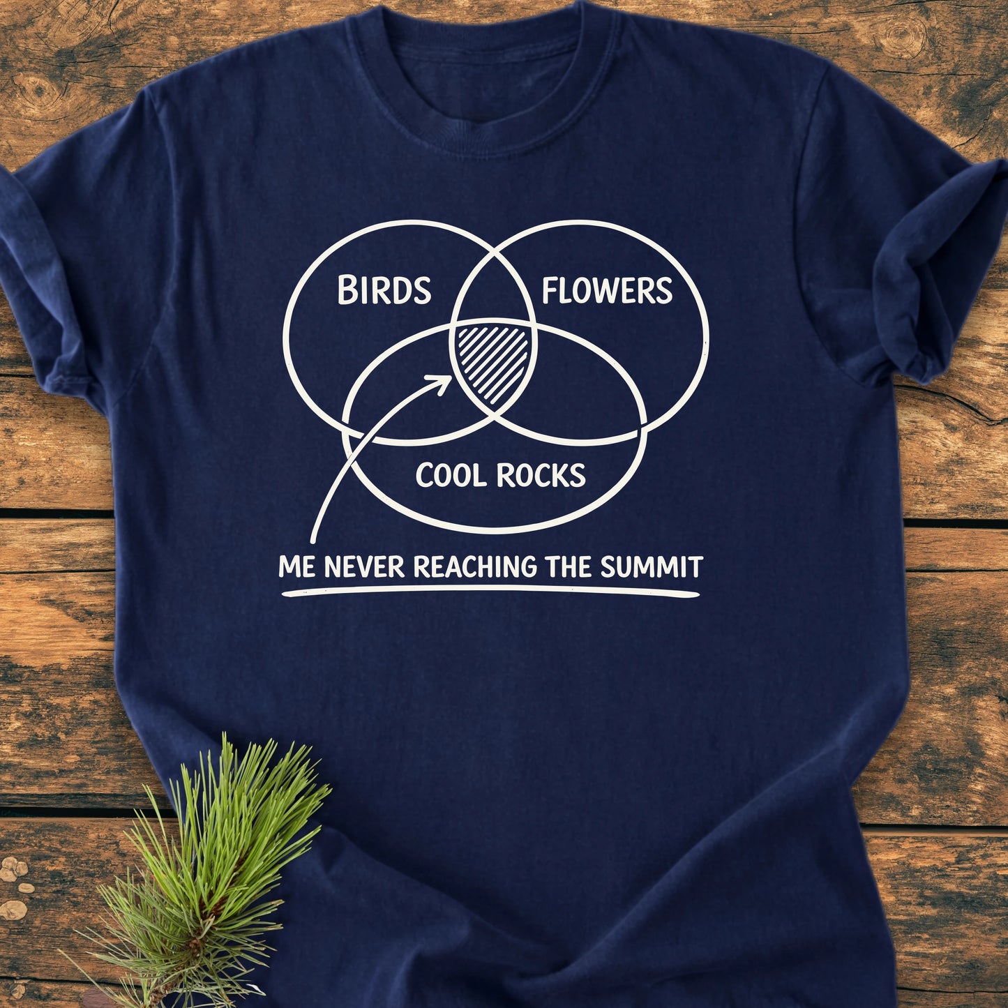Navy-blue 1416 Easily Distracted Hiker T-shirt with a humorous nature-themed Venn diagram design, laid on wood. Features relaxed unisex fit, vintage wash, and durable build.