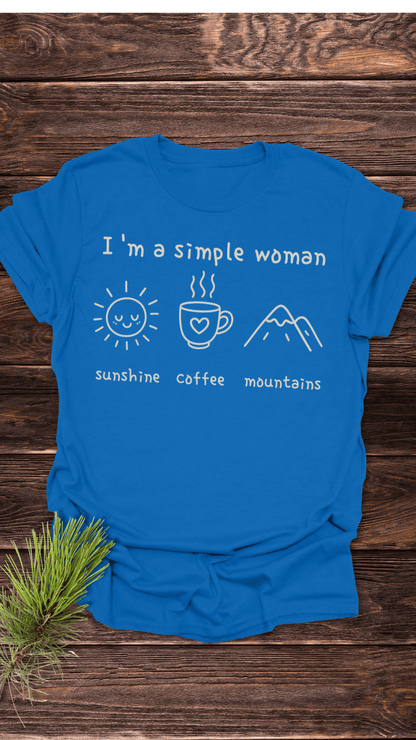 I'm A Simple Woman - Sunshine Coffee Mountains T-Shirt on wooden surface, featuring white icons of a sun, coffee mug, and mountains, highlighting comfort and durability.