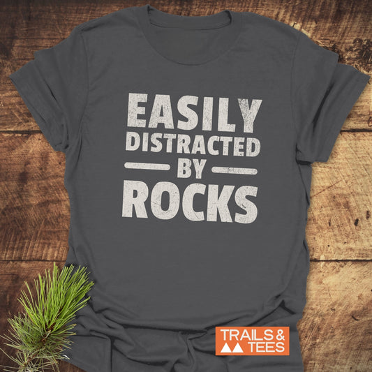 Easily Distracted By Rocks T-Shirt with white text on grey fabric, featuring durable DTF prints, taped shoulders, and ring-spun cotton for comfort and reliability.